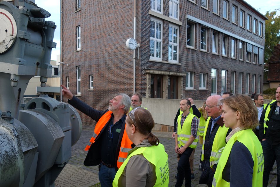 Personen betrachten ein großes Bauteil 